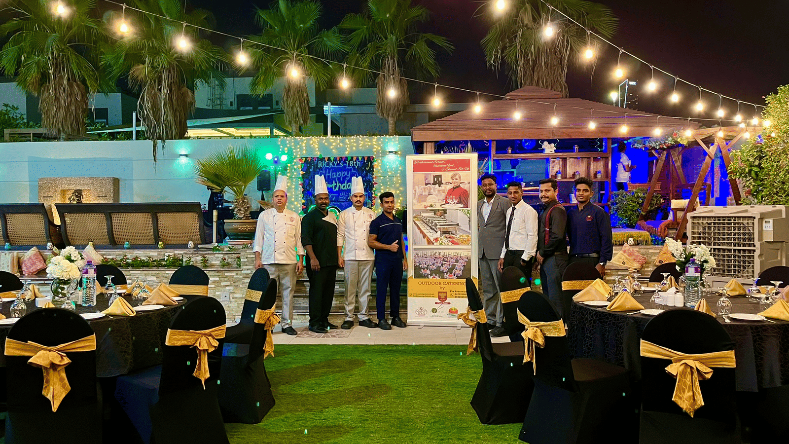 Outdoor dining area with guests and string lights at Marco Polo Hotel.