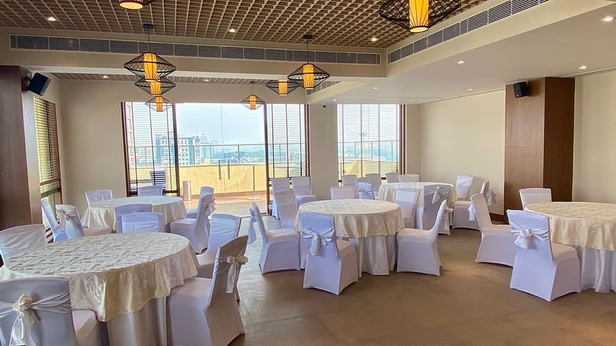 An image of a banquet hall with its seating arrangement and subtle decoration with lighting - Hideaway banquets & Lawns, Greater Noida