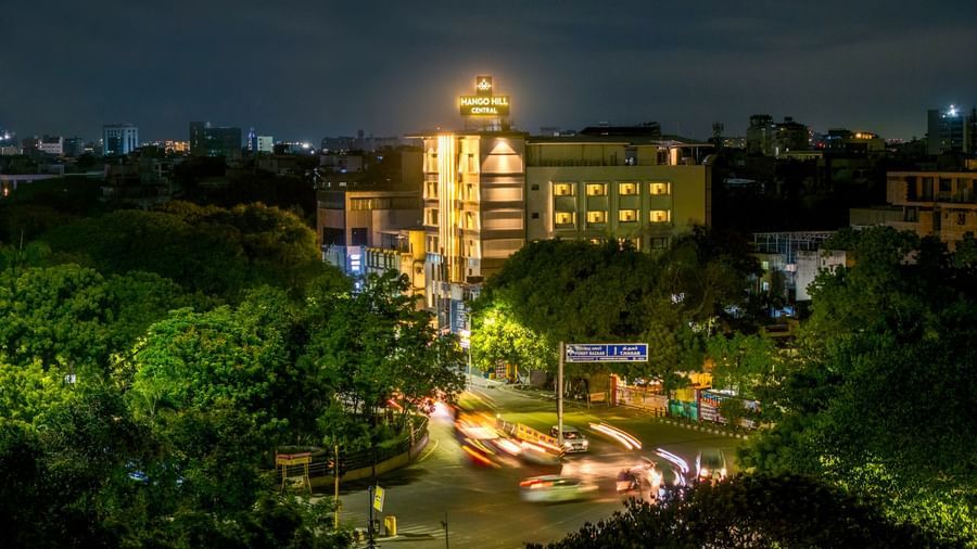 An aerial night view of Mango Hill Central, Chennai, showing the illuminated hotel building and outdoor seating area.