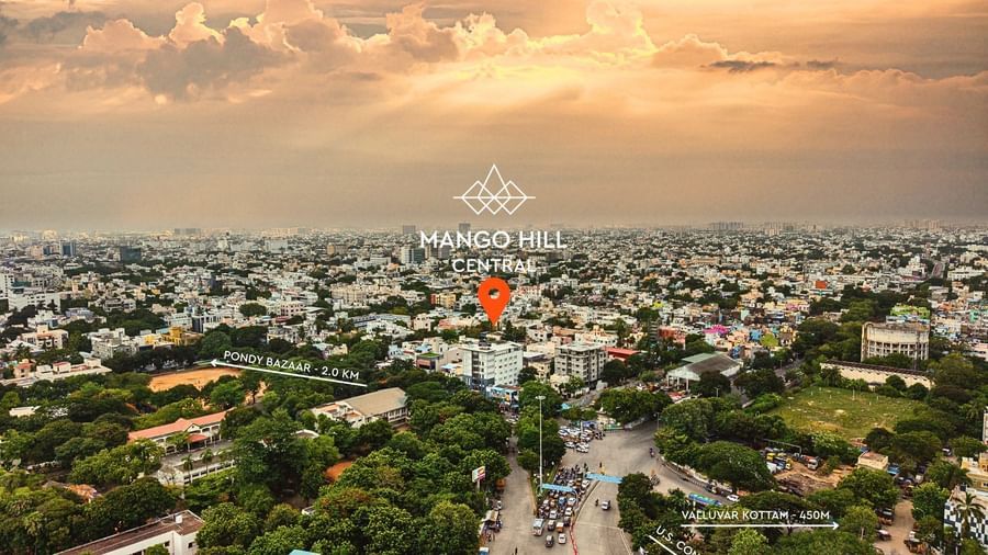 An aerial view of the city of Chennai at sunset. A red marker is visible on one of the buildings.