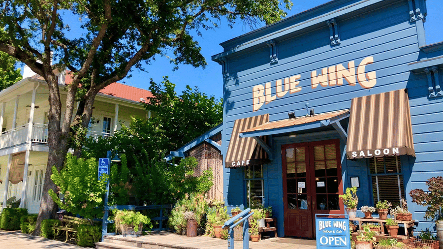 Entrance of the Blue Wing Saloon of Tallman Hotel accompanied by a tall tree