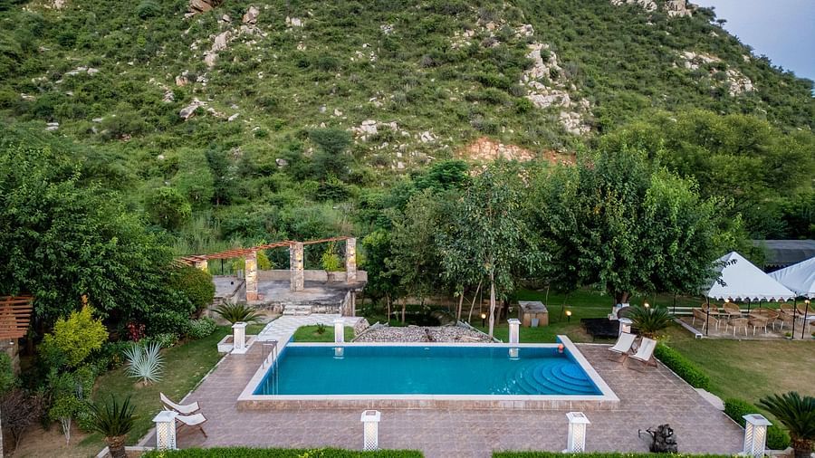 A pool surrounded by greenery with mountains in the background at Valley by Grassfield.