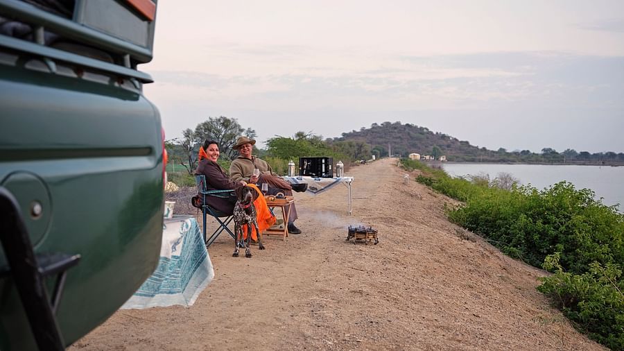 image of a couple sitting in front of the lake with a small bonfire in front of them