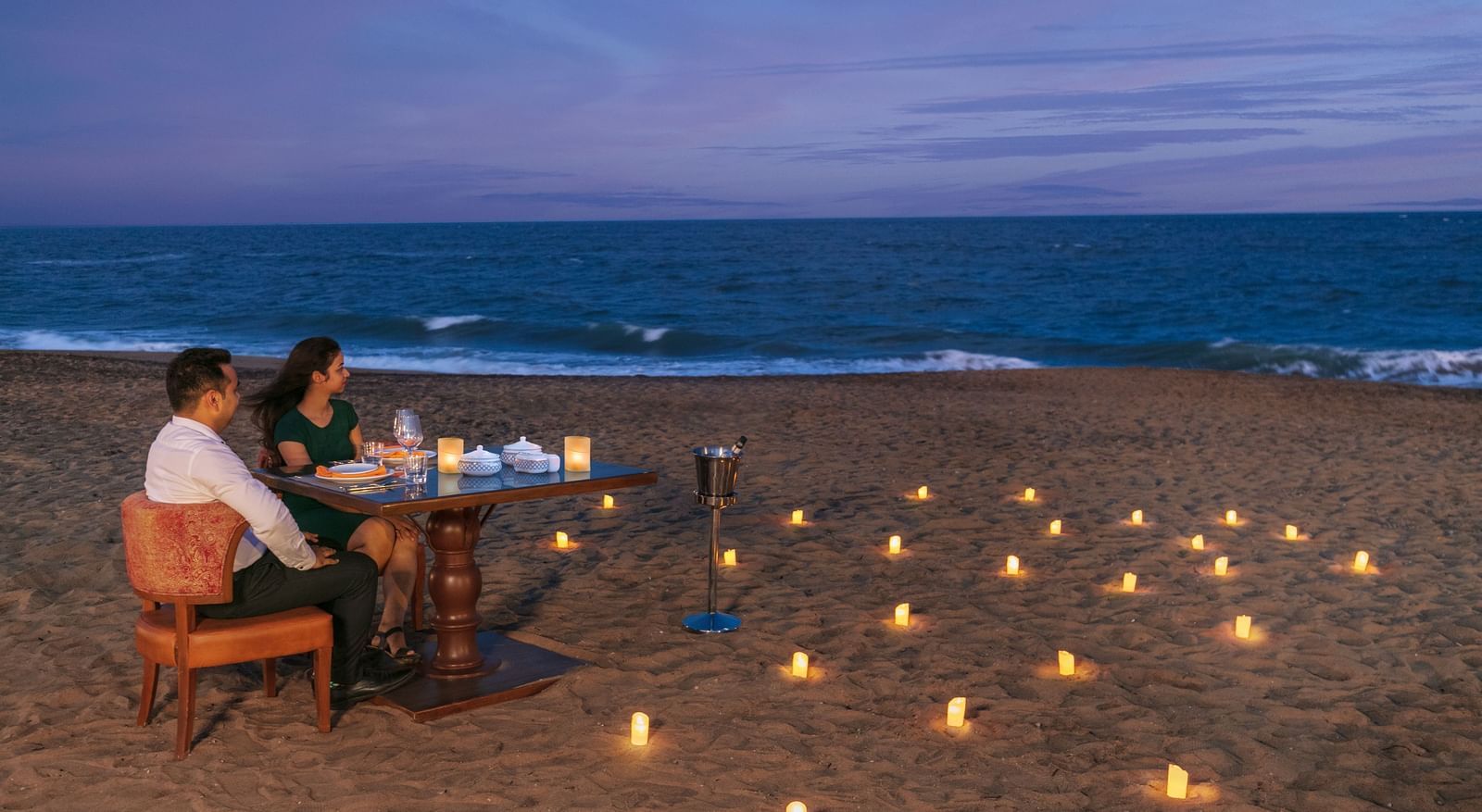 A romantic candlelight dinner setup on a pristine sandy beach – Kaldan Samudra Palace, one of the top 5 Star Restaurants in Mahabalipuram ECR, offering an unforgettable dining experience by the sea