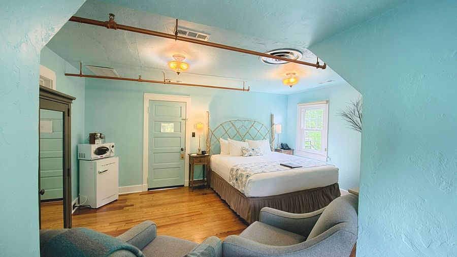 a beautiful room with calming tones featuring a double bed and a mini refrigerator in the room - Historic Tapoco Lodge