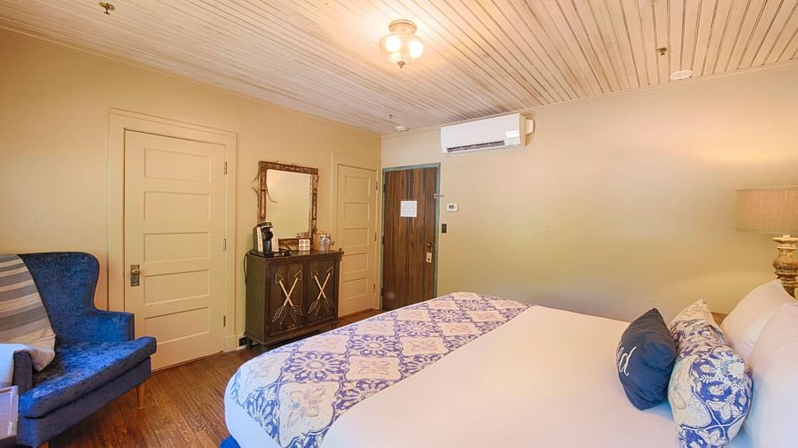 side view of a bedroom featuring a double bed along with a blue coloured arm chair and a wall mounted split air-conditioner - Historic Tapoco Lodge