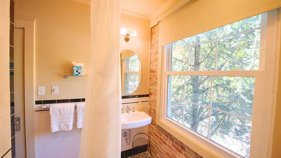 a bathroom with bricked wall along with a wide window throwing ample of natural sunlight in the room - Historic Tapoco Lodge