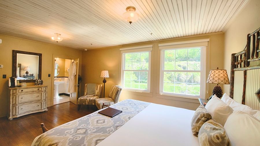 a bright bedroom with ample of natural light coming form the windows beside the double bed - Historic Tapoco Lodge