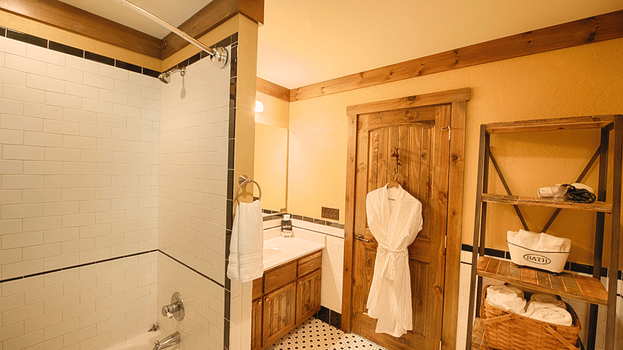 a bathroom featuring a storage shelf with fresh linens and a wooden door with a bathrobe hanging on it - Historic Tapoco Lodge