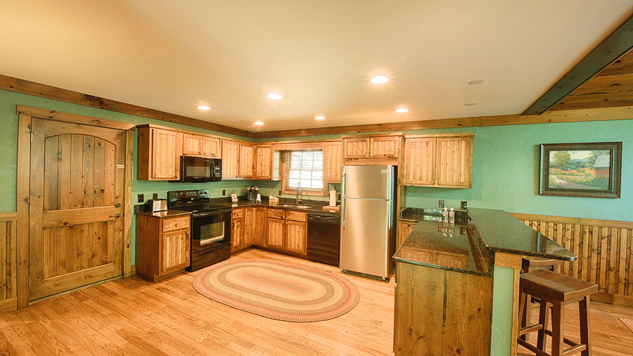 a fully-equipped kitchen with modern appliances and a service counter in the corner with elevated chairs - Historic Tapoco Lodge