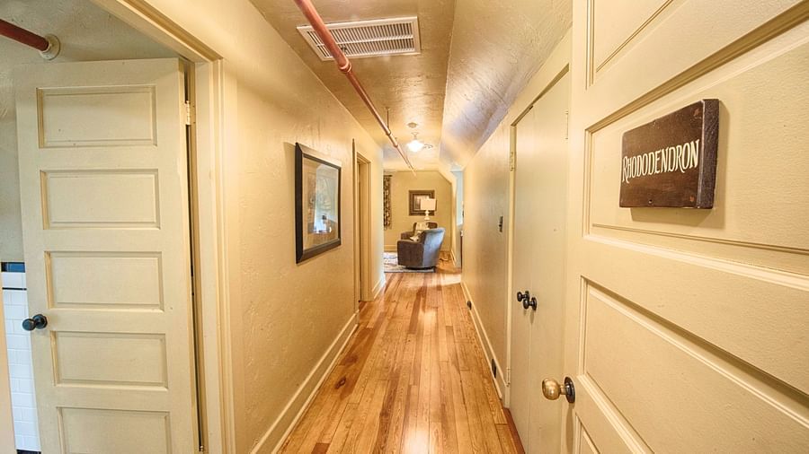 the corridor with wooden flooring and white colored doors leading to various rhododendron suites - Historic Tapoco Lodge
