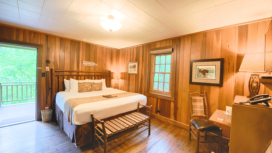 full view image of the a bedroom with a couple bed along with a small seating are in front of the bed - Historic Tapoco Lodge