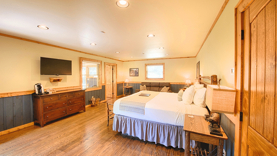 a beautiful room with a flat screen television and a wooden shelf placed opposite to a double bed - Historic Tapoco Lodge