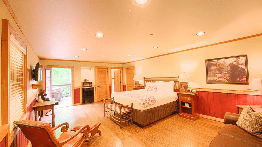 a beautiful room featuring a double bed with a seating area and a cushioned arm chair in the side  - Historic Tapoco Lodge