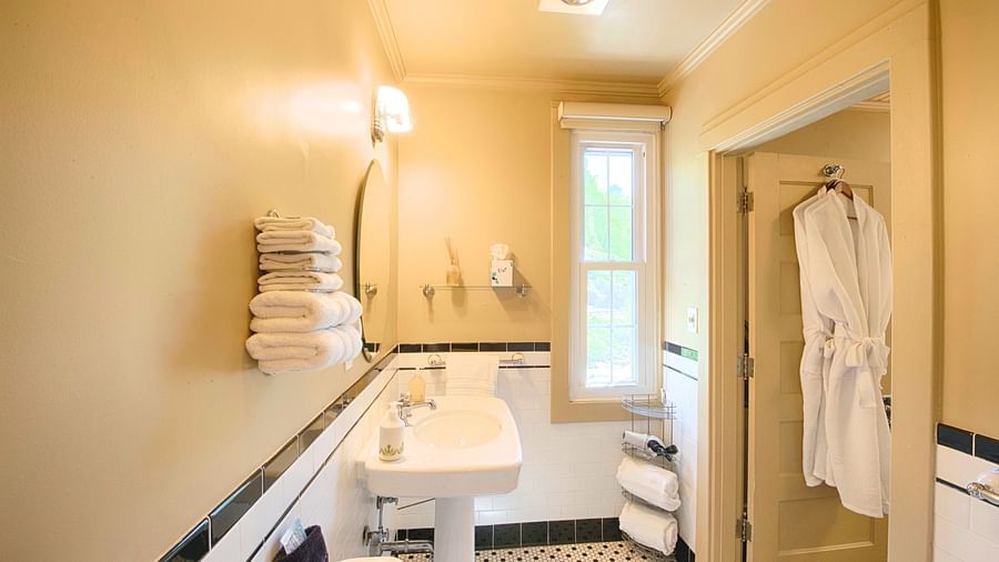 a small bathroom with a wash basin with fresh towels staked besides it - Historic Tapoco Lodge