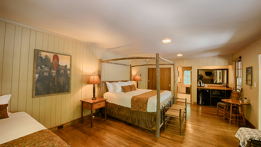 a cozy bedroom with a wall mounted art piece besides a double bed and a dressing table at the far end of the room - Historic Tapoco Lodge