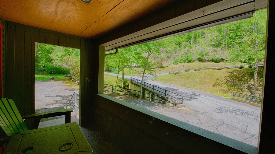 an indoor porch with a wooden armchair facing towards the pathway outside the cabin - Historic Tapoco Lodge
