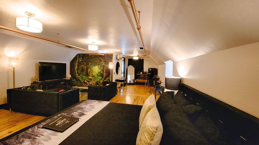 a suite with black linen spread over the double bed with a common seating area and a full screen television - Historic Tapoco Lodge