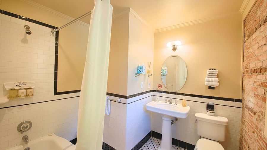 a bathroom featuring a commode along with wash basin with a circular mirror above it - Historic Tapoco Lodge