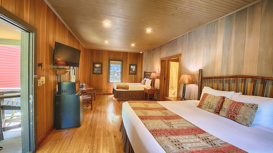two double beds placed in a bedroom with a door in the middle of them - Historic Tapoco Lodge