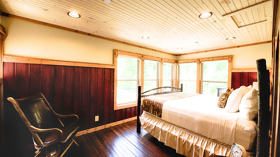 a double bed placed in front of huge windows illuminating the entire room with natural light - Historic Tapoco Lodge