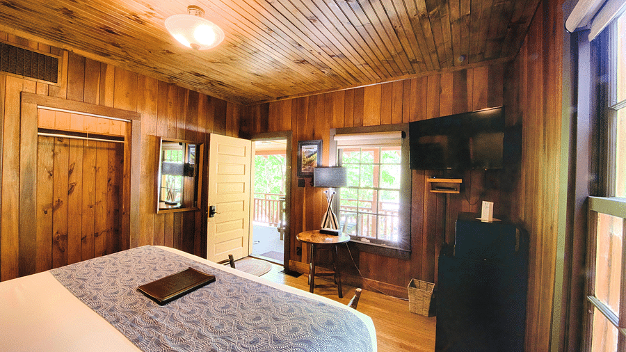 a wooden cabin overlooking a double bed with wooden panel ceiling above it - Historic Tapoco Lodge