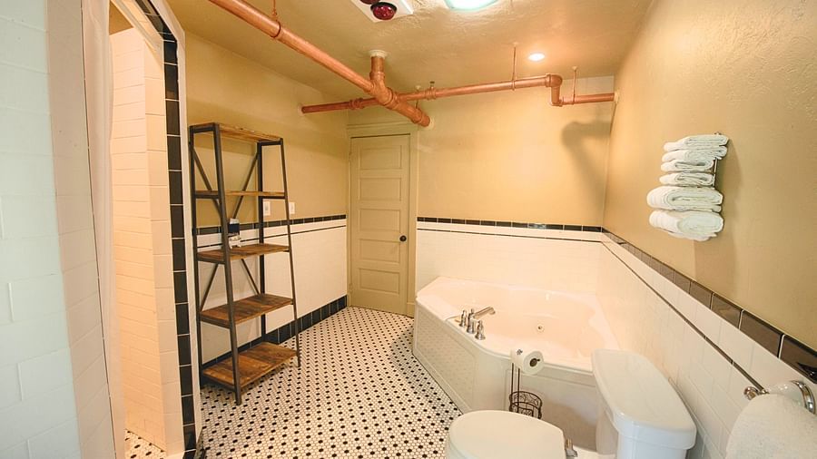 corner view image of the bathroom featuring a commode and a bathtub with towels towed above the toilet - Historic Tapoco Lodge