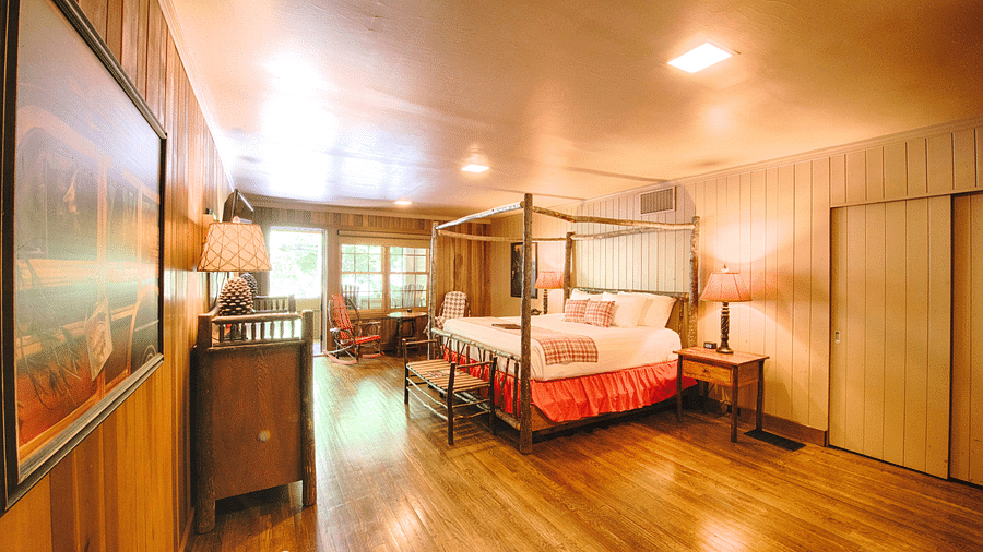 corner view image of a bedroom with a wall mounted picture along with a double bed and a door allowing bright natural light into the room - Historic Tapoco Lodge