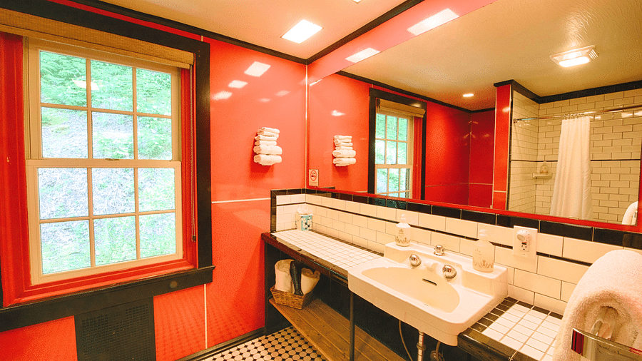 a bathroom with a washbasin along with a huge wide mirror above it - Historic Tapoco Lodge