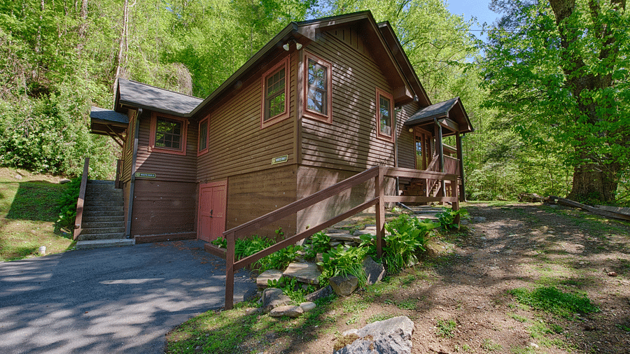 corner view of a cabin with wooden exterior surrounded by lush green trees - Historic Tapoco Lodge