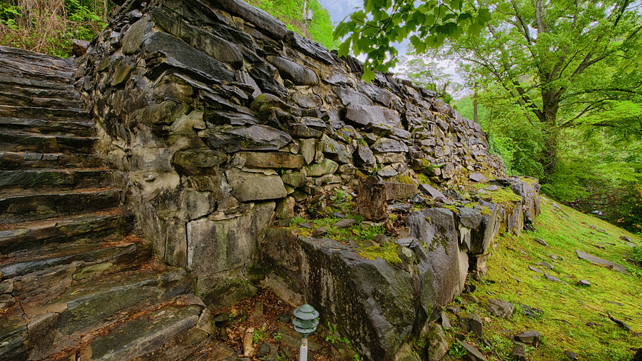 a huge stone wall with a stairway going uphill - Historic Tapoco Lodge