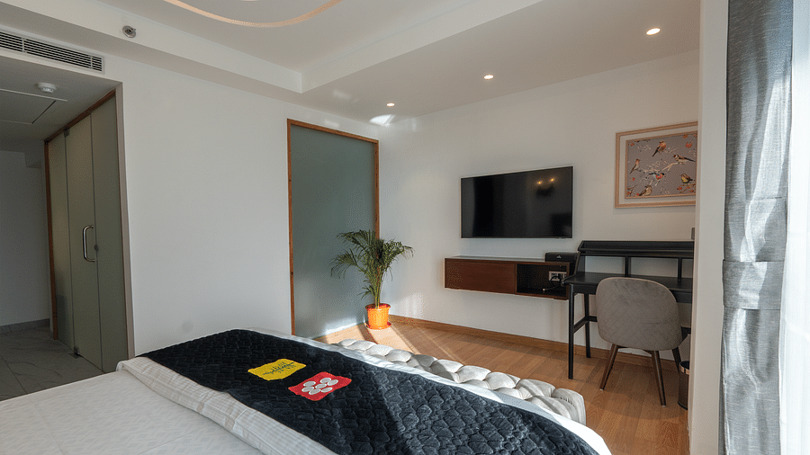an image of side view of a bedroom with a television and a working table and chair