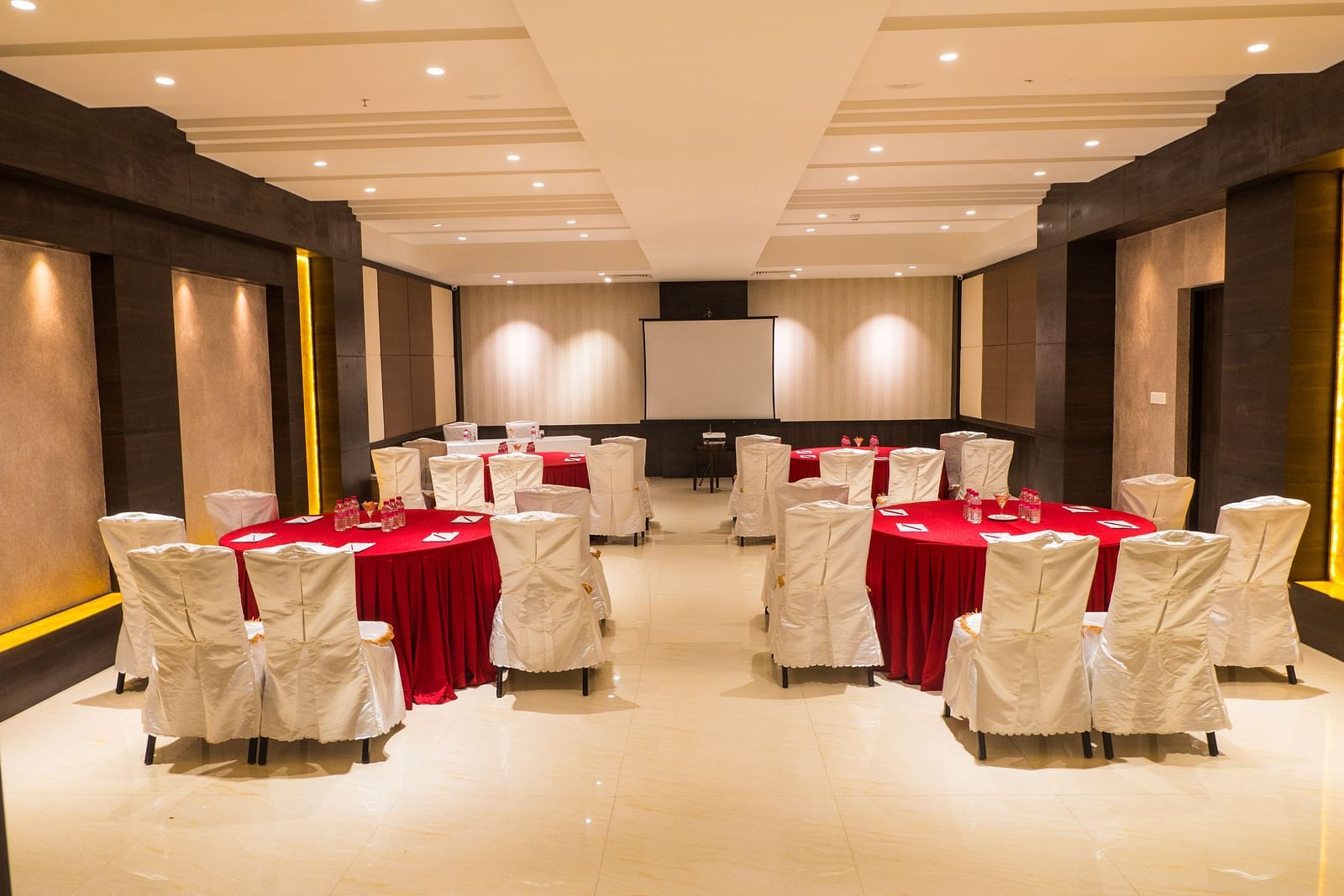 event hall with red tables and white satin chairs of ASR Parklane, Hosur