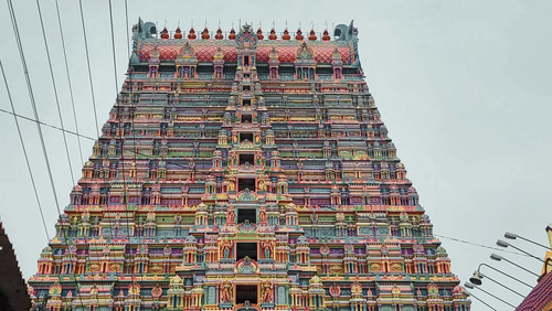 A majestic temple gopuram towers upwards, adorned with colourful sculptures and flanked by power lines, it is one of the famous temple in Pollachi.