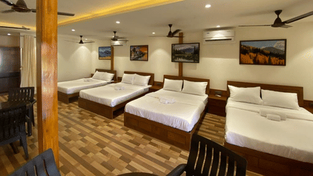 Spacious group accommodation featuring four double beds, wooden flooring, and warm recessed ceiling lighting - DAN Resorts & Weddings, Palghar