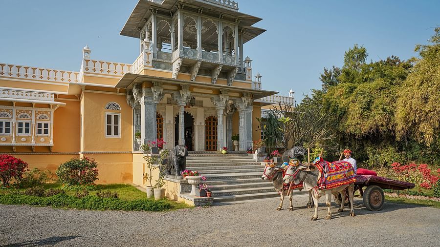 image of a building constructed in the rajasthani style surrounded by bright green trees at dev shree, deogarh