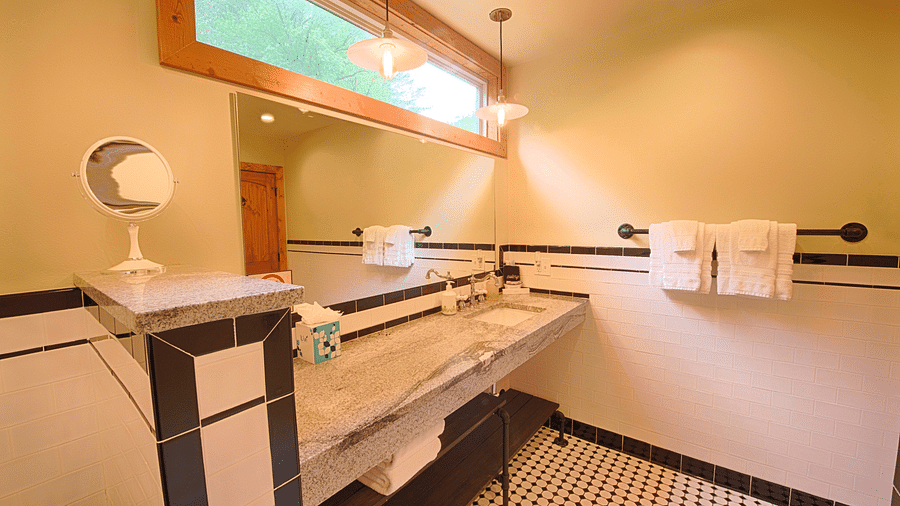 the washbasin with a wide mirror being featured in a bathroom along with a narrow window above it throwing natural light - Historic Tapoco Lodge