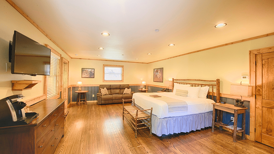a room with a comfortable double bed and a wall mounter television with ample lighting - Historic Tapoco Lodge