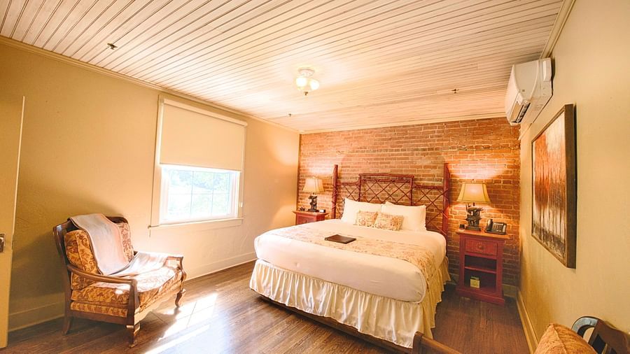 full view image of a bedroom featuring a bricked wall behind the double bed - Historic Tapoco Lodge