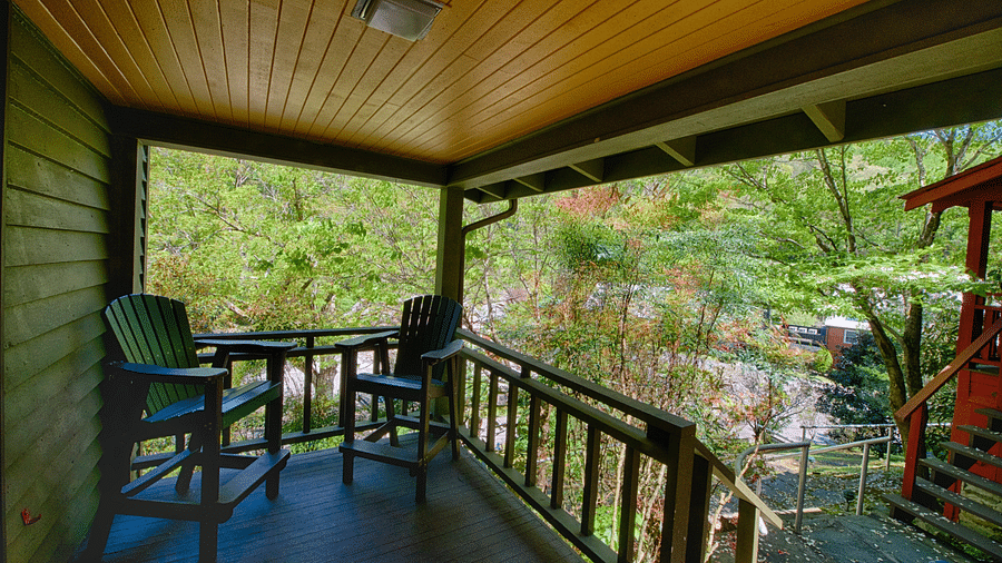 a porch with two chairs places in the corner with a mesmerizing views of the nature - Historic Tapoco Lodge