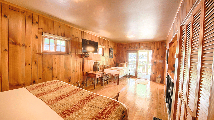 corner view of a bedroom featuring two beds along with bright natural light illuminating the room from the entrance - Historic Tapoco Lodge