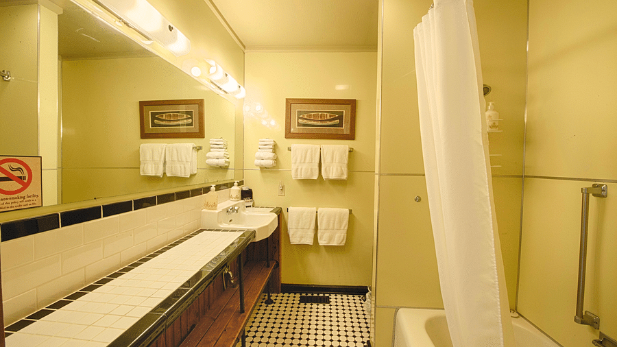 a wide angle shot of a bathroom featuring a bathtub and fresh linens hanging besides the wash basin - Historic Tapoco Lodge