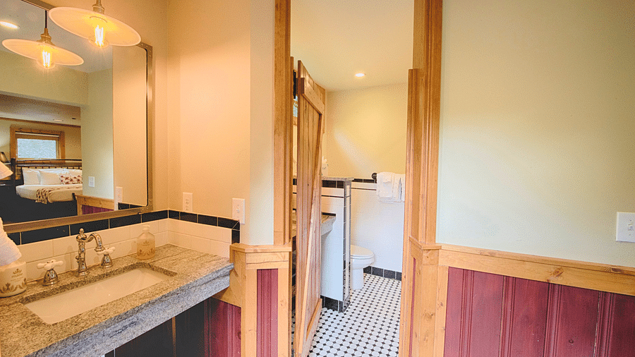 a bathroom with a wash basin and mirror along with a door leading to the commode - Historic Tapoco Lodge