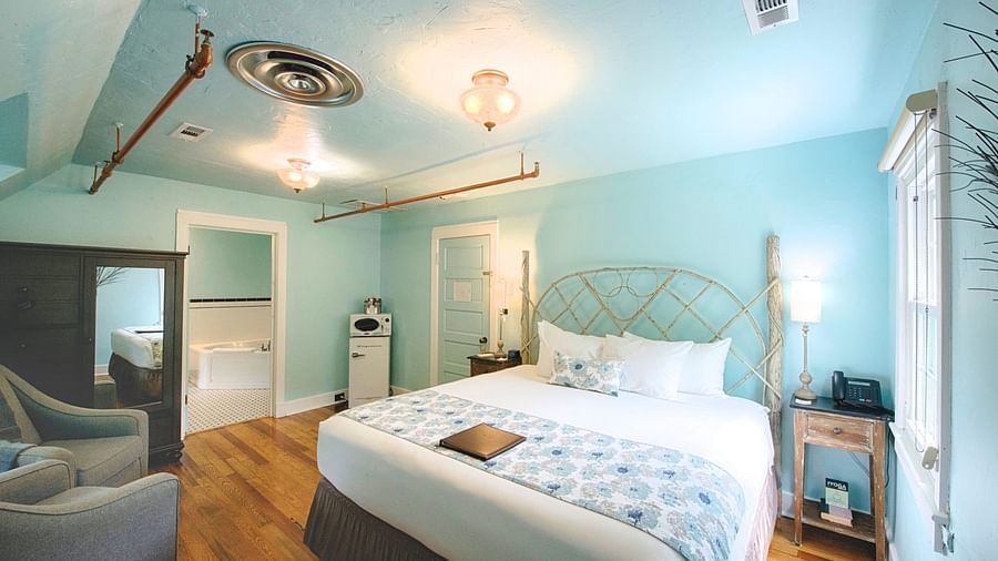 corner view image of the bedroom featuring a comfortable double bed with a window right by the bedside - Historic Tapoco Lodge