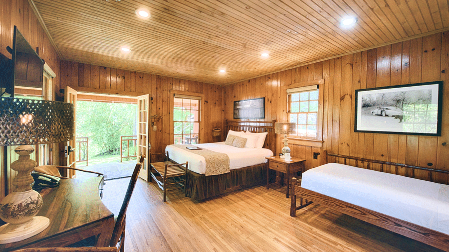 a room featuring a huge entrance to the room with wooden interiors featuring a double bed and a work desk and chair - Historic Tapoco Lodge