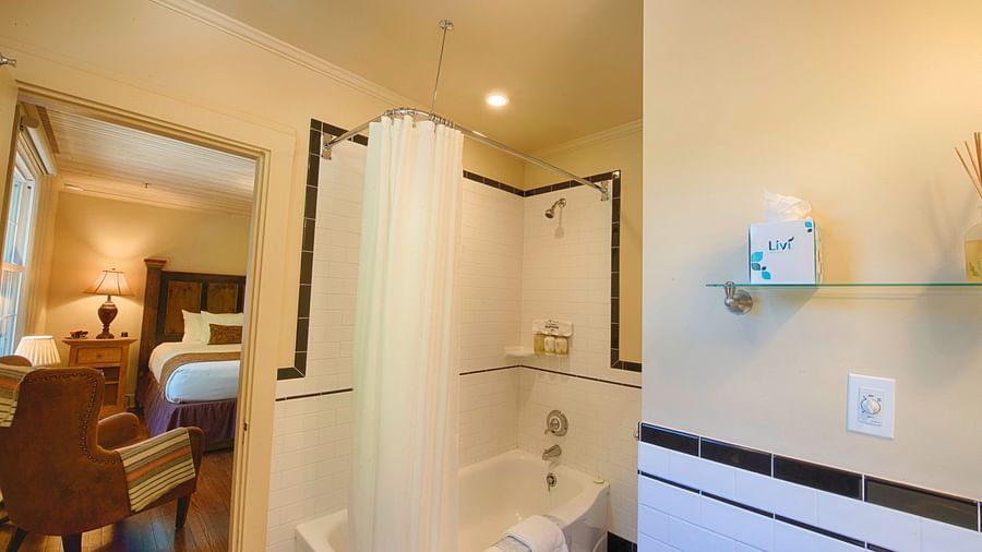 a door opening into the bathroom with a full size bath tub beside it - Historic Tapoco Lodge