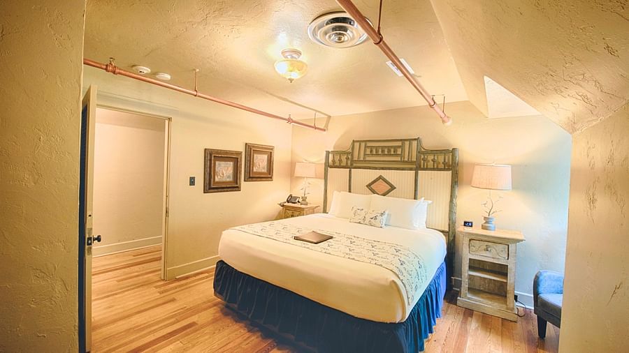 full view image of the bedroom of rhododendron suite featuring a huge double bed with bedside table beside it - Historic Tapoco Lodge
