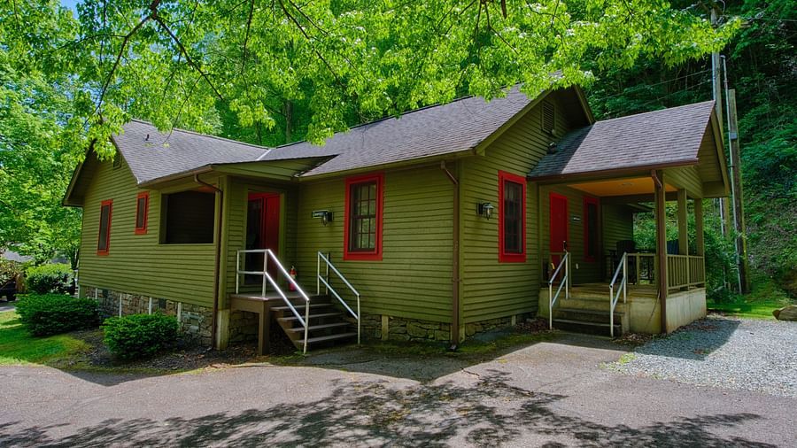 facade image of a cabin with green exterior walls camouflaging with the lush green surroundings - Historic Tapoco Lodge