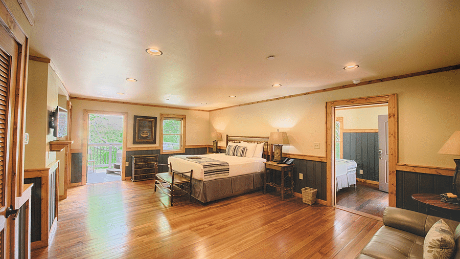 a bedroom with wooden flooring featuring a double bed in the middle - Historic Tapoco Lodge