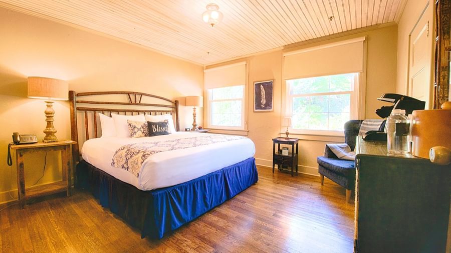 full view image of a room featuring a double bed with bed side tables along with a wooden cabinet in front of it - Historic Tapoco Lodge